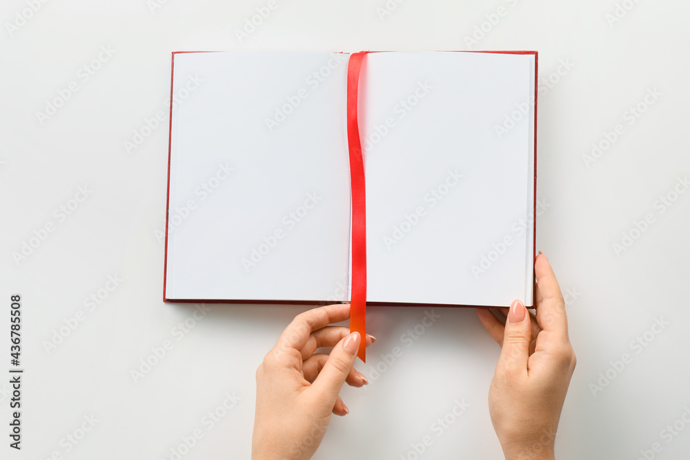 Female hands and blank book with bookmark on white background