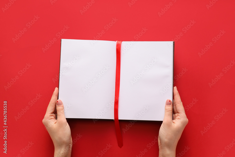 Female hands and blank book with bookmark on color background