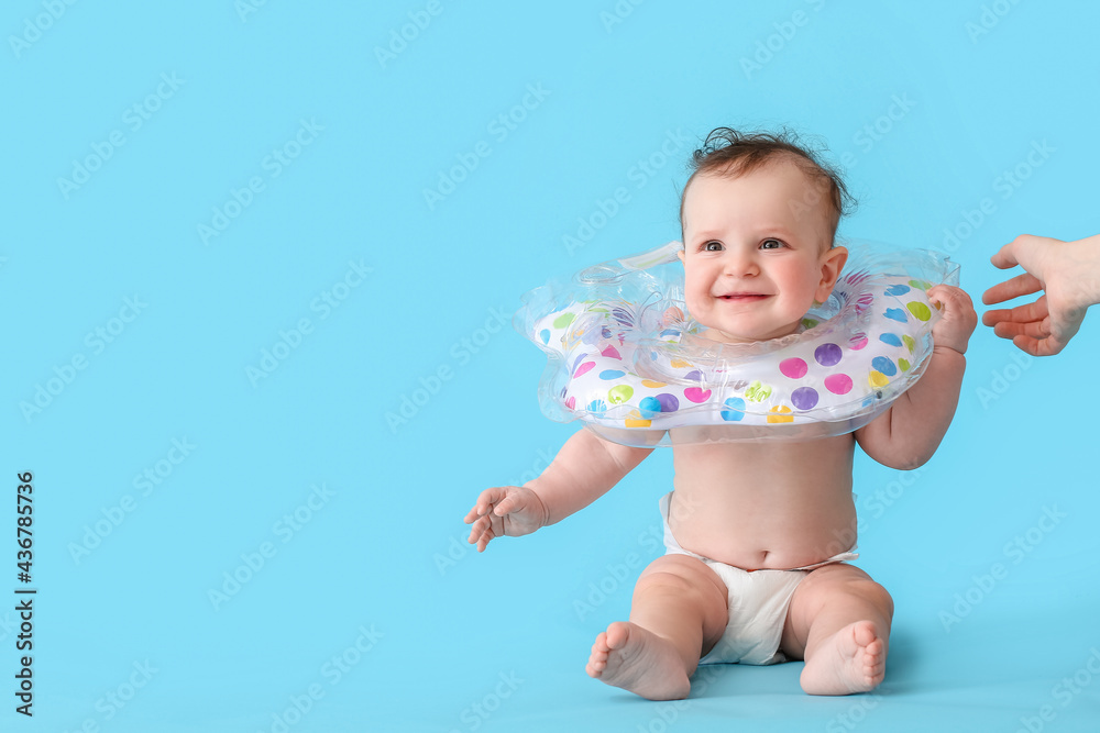 Cute baby with inflatable ring on color background