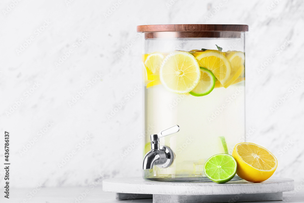 Jug of tasty cold lemonade on light background