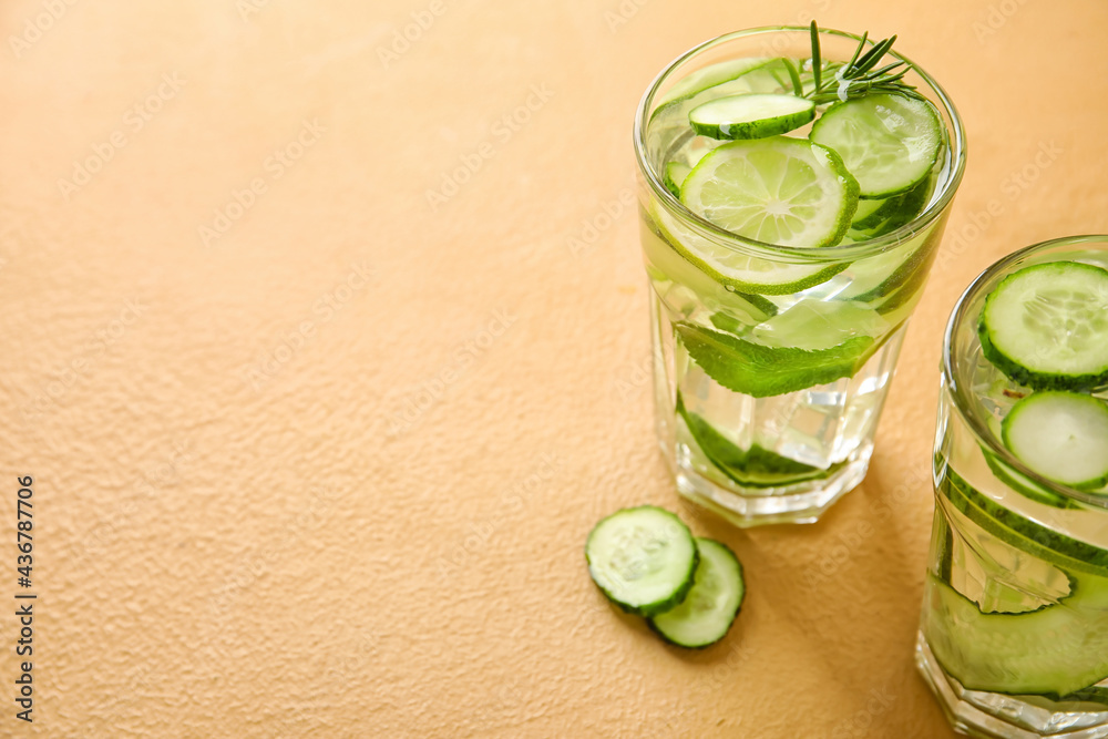 Glasses with cucumber lemonade on color background