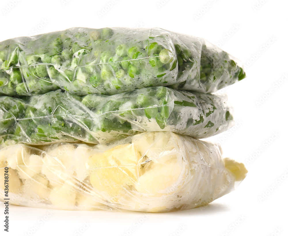 Plastic bags with frozen vegetables on white background