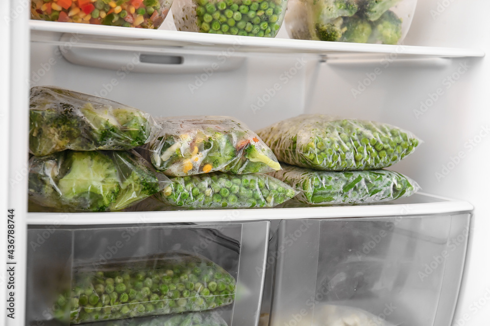 Containers and plastic bags with vegetables in refrigerator