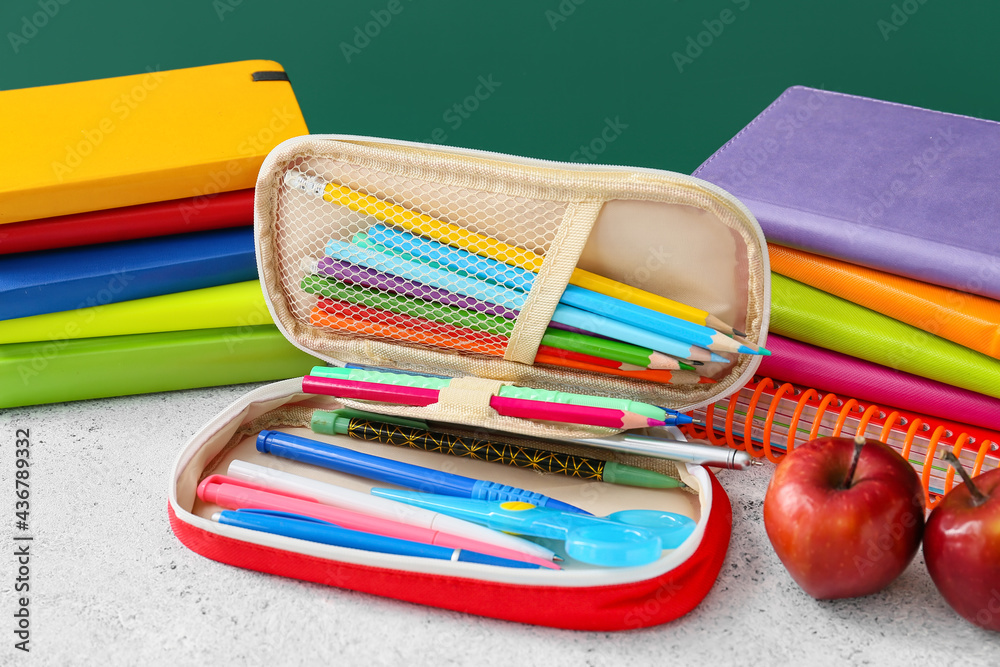 Pencil case and stationery on color background