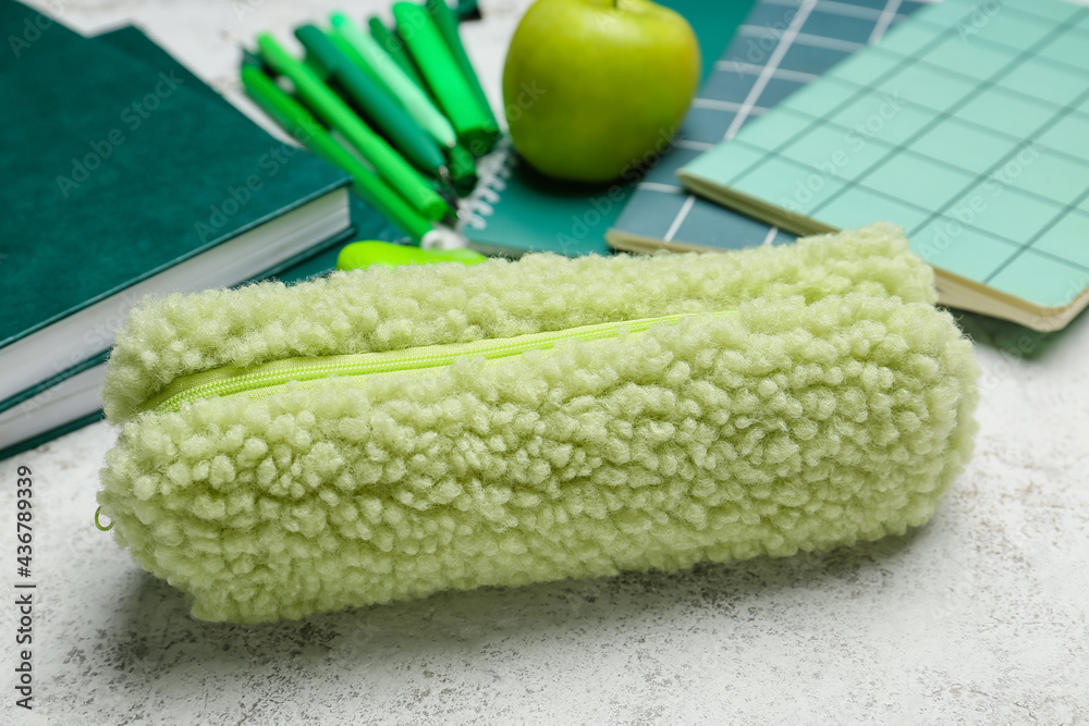 Pencil case and stationery on light background