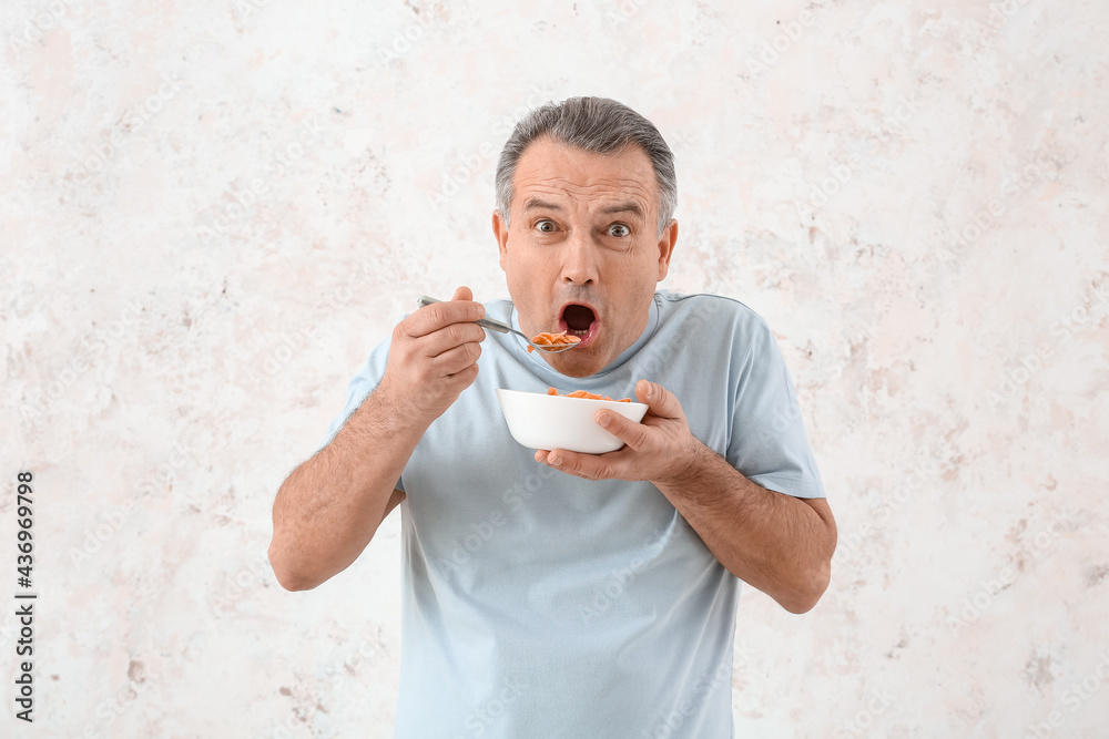 Senior man eating cornflakes on white background