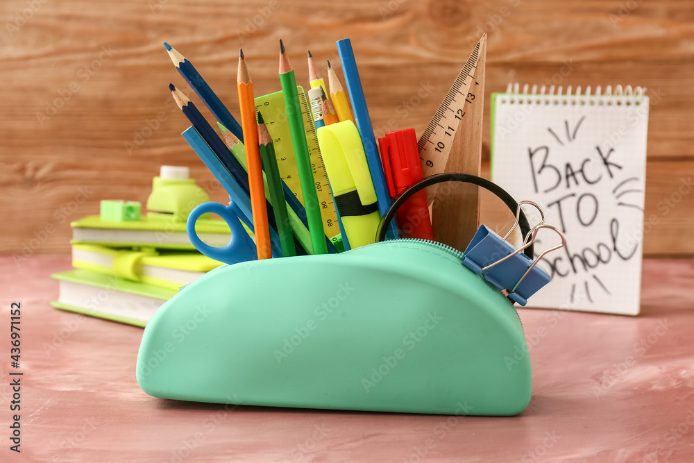 Pencil case with stationery on color background