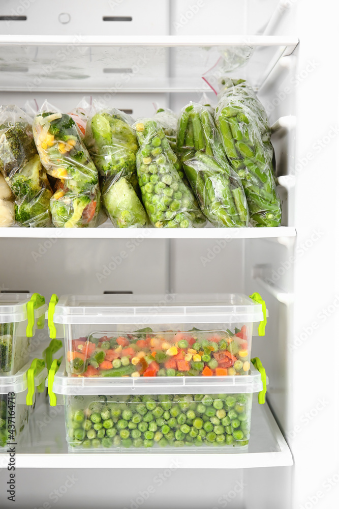 Containers and plastic bags with vegetables in refrigerator