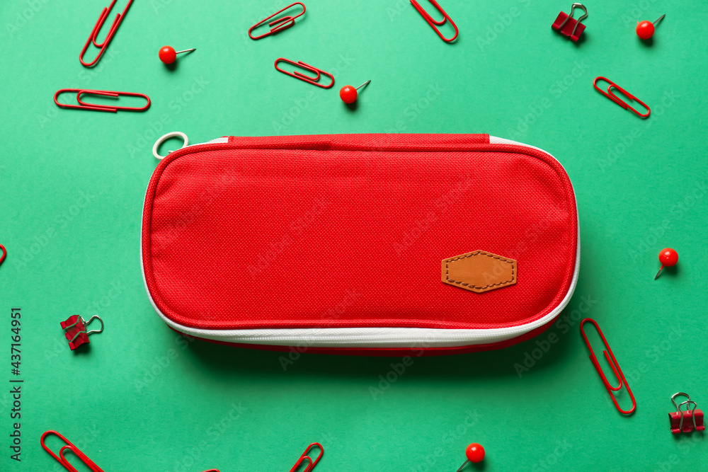 Pencil case, clips and pins on color background