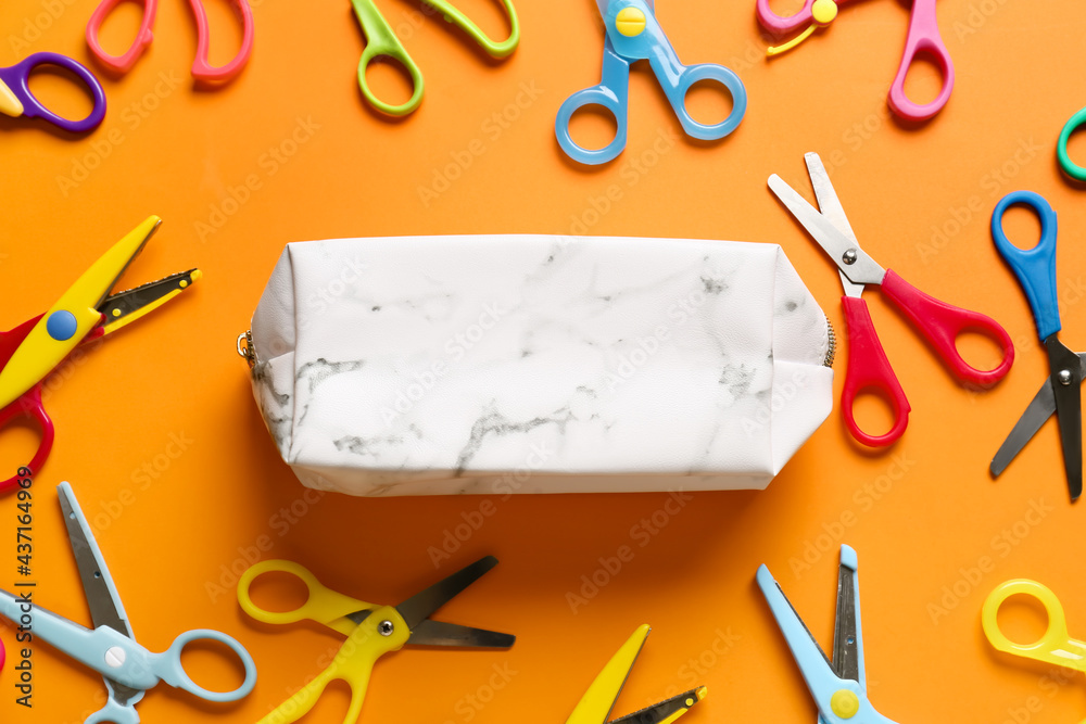 Pencil case and scissors on color background