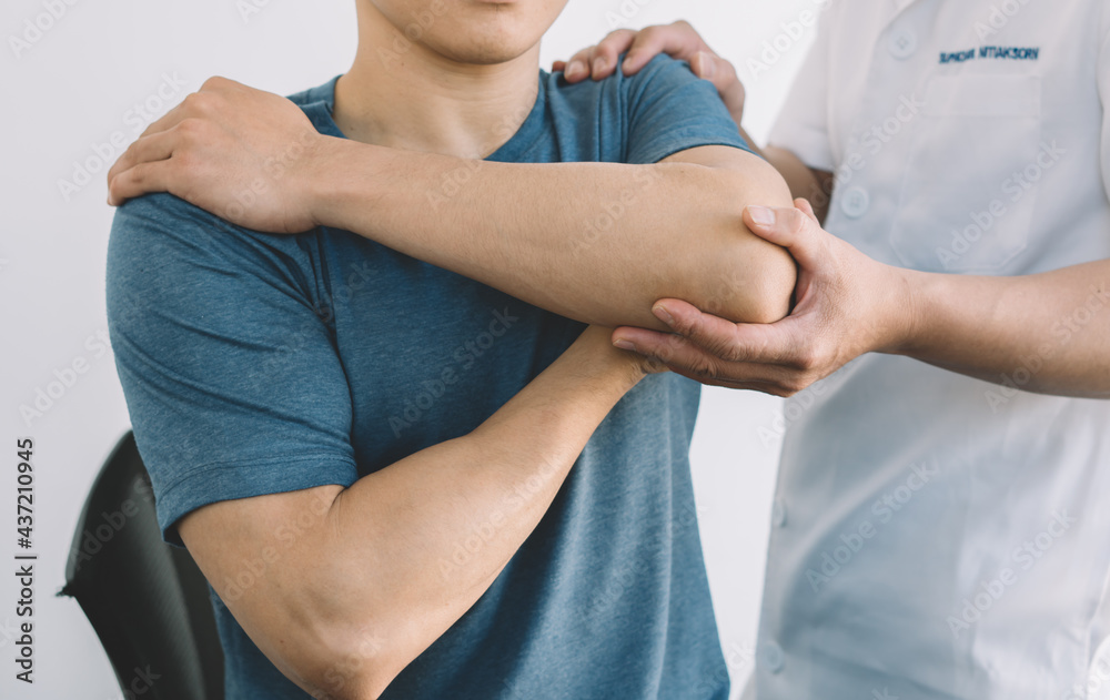 A doctor or physical therapist examines elbow pain and gives advice within a rehabilitation center.