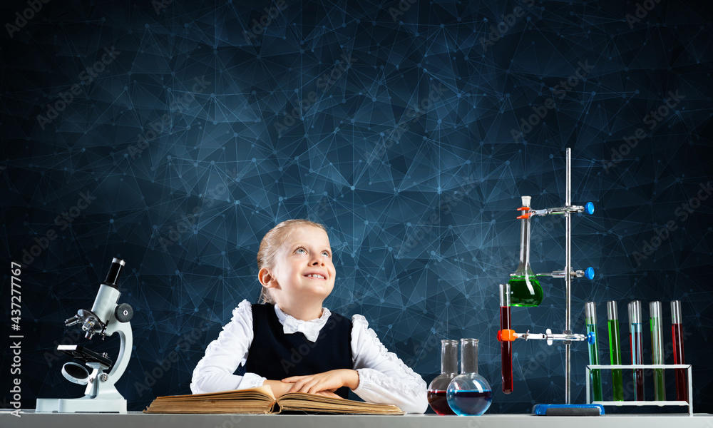 Smiling little girl sitting at desk with open book