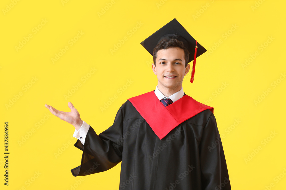 Male graduating student showing something on color background