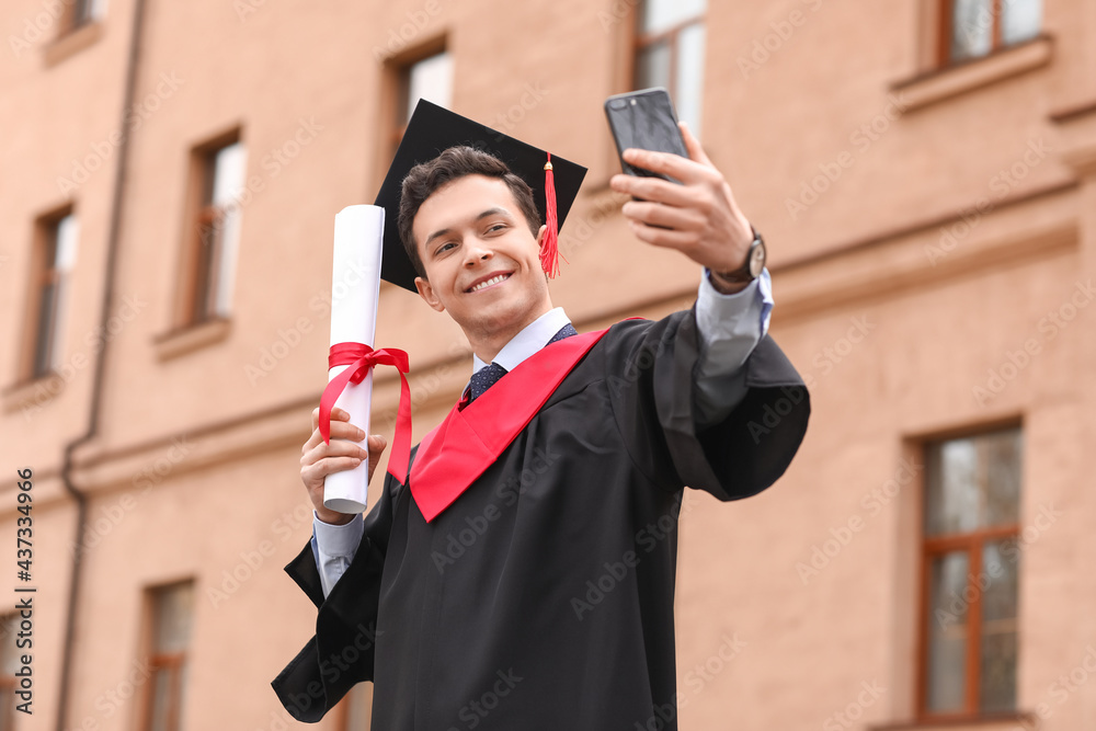 Male graduating student taking selfie outdoors