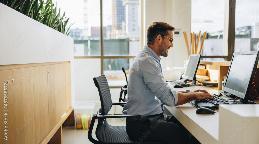 Smiling young man working at his desk