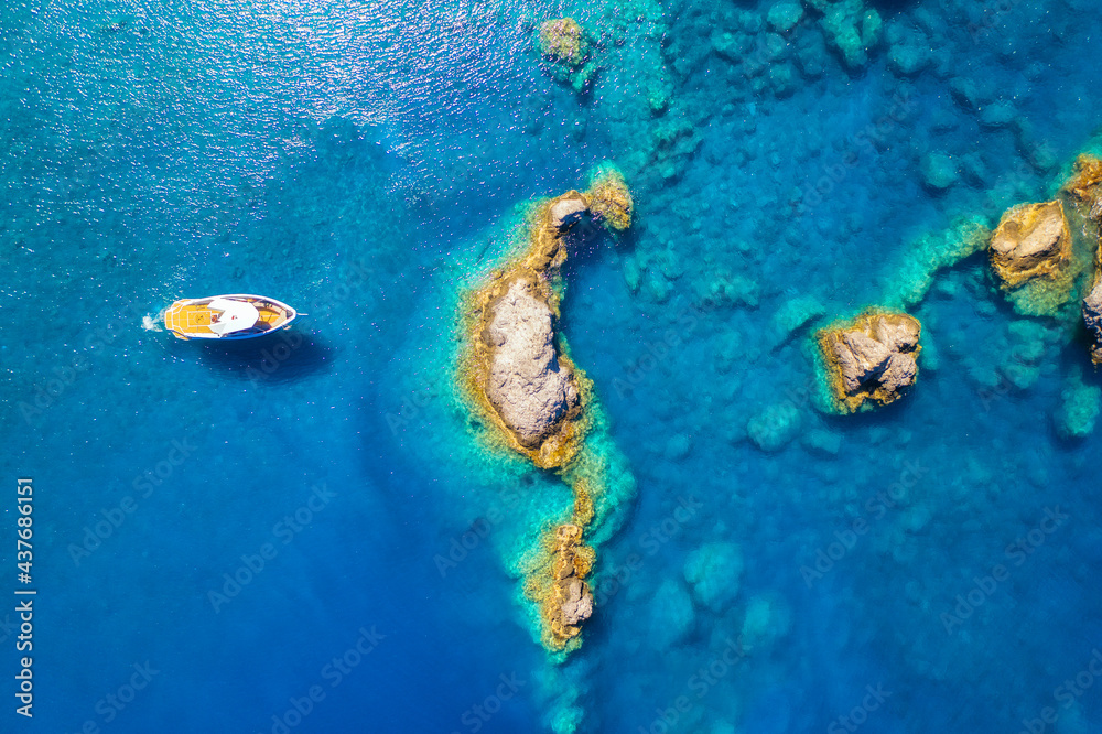 夏日日出时，蓝色海面上的快艇。海湾上摩托艇的鸟瞰图，清澈的天青中的岩石