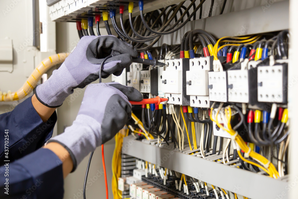 Electrician engineer tests electrical installations and wires on relay protection system. Adjustment