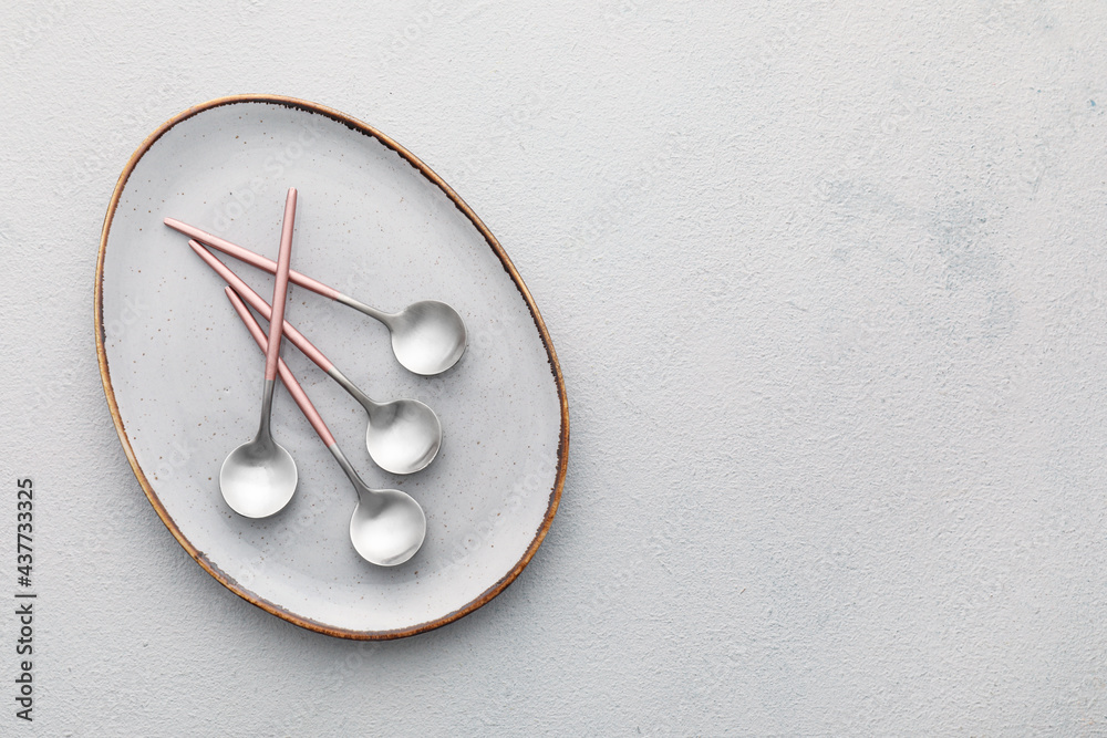 Clean spoons with plate on light background