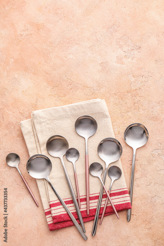 Clean spoons with napkin on color background