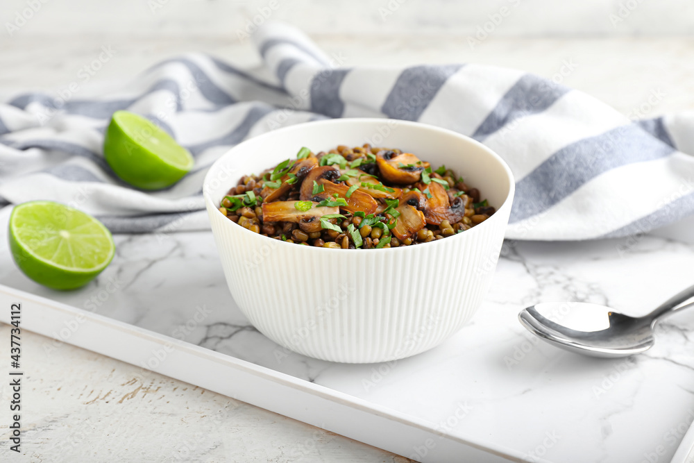 Bowl of tasty cooked lentils and mushrooms on table