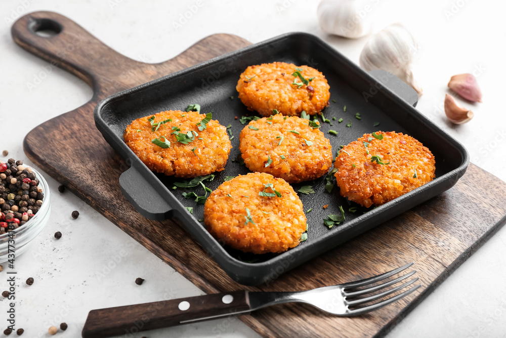 Frying pan with tasty lentil cutlets on table