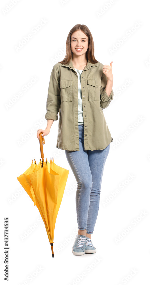 Stylish young woman with umbrella showing thumb-up on white background