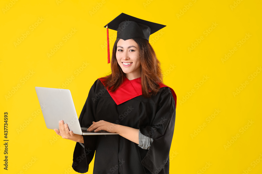 Female graduating student with laptop on color background