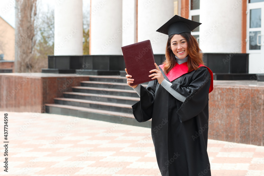 Female student in bachelor robe and with book on her graduation day