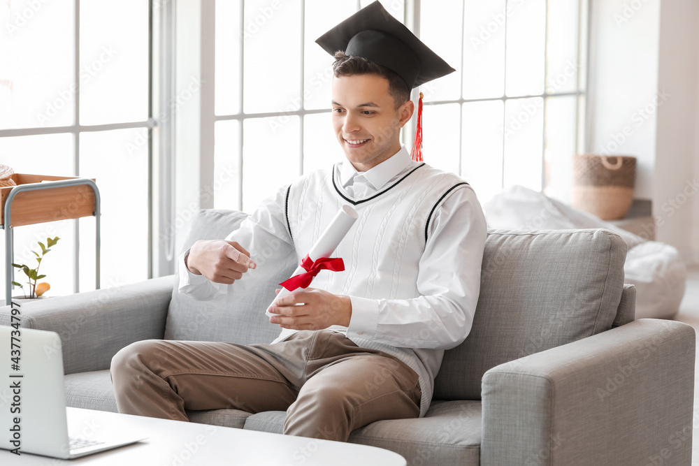 Happy male student on his graduation day at home. Concept of online education