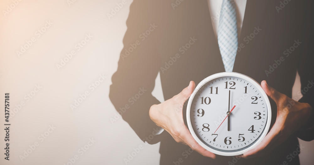 Concept of saving time, Businessman holding a clock against time 6 am in the morning on the White ba