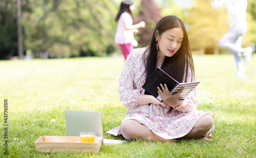 夏天或春天在外面工作和WFH概念，年轻漂亮的亚洲女人读书和