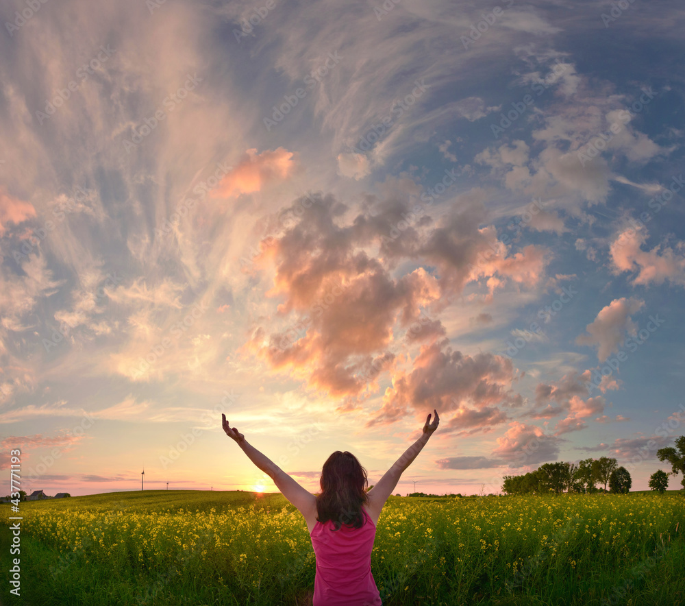 Happy woman enjoys beautiful sunset on flower field