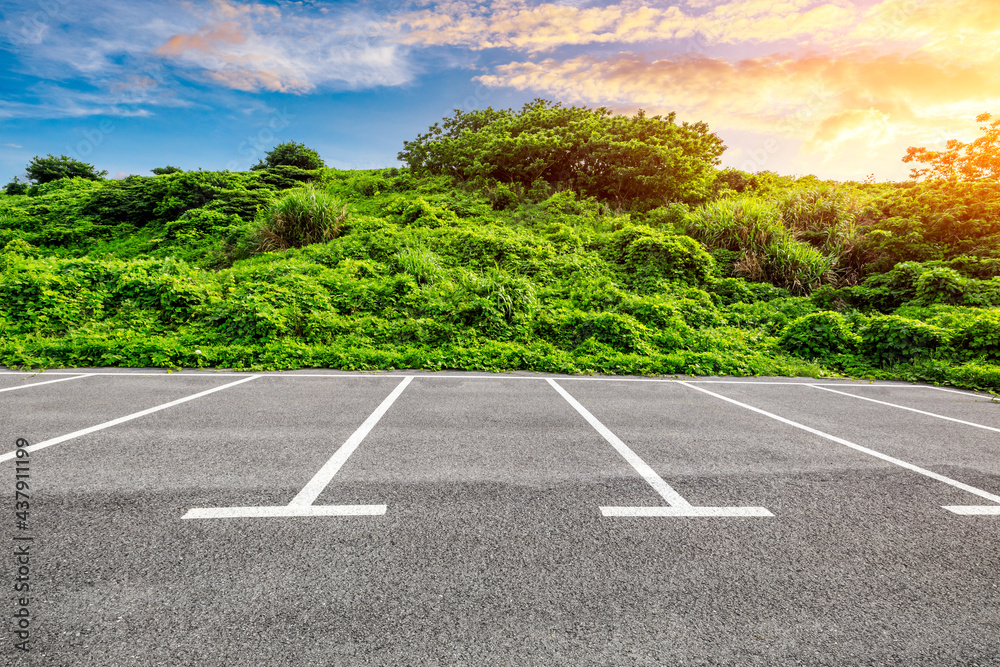 Asphalt parking lot and green mountain nature landscape at sunrise.