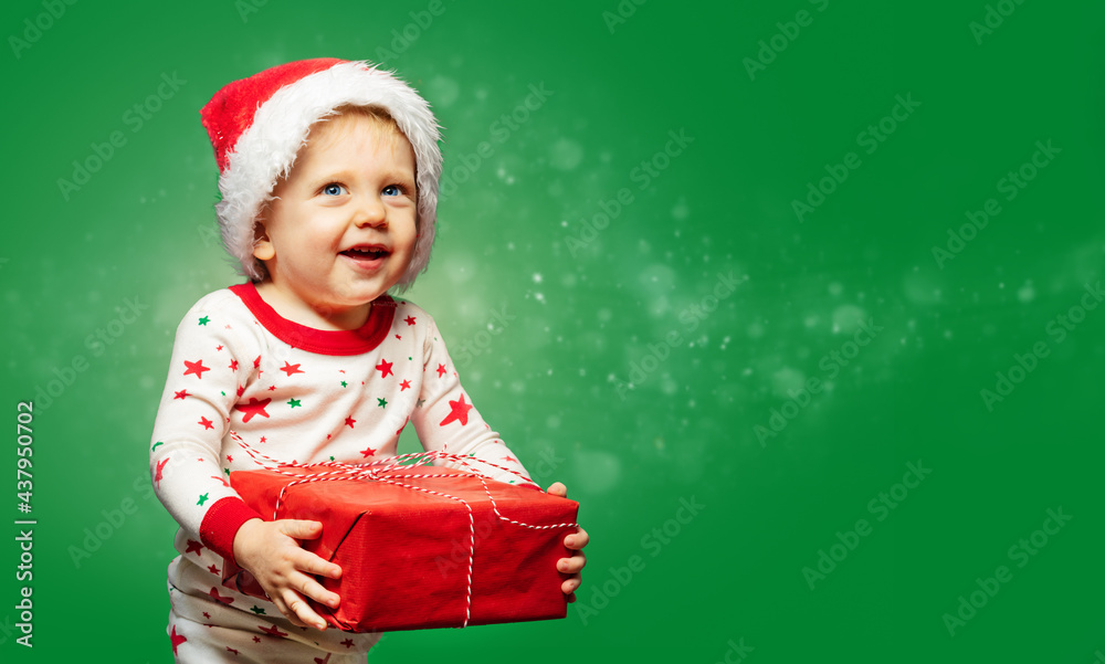 Toddler boy hold present box wearing Santa hat