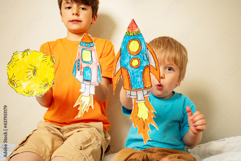 Two cute boys play with rockets drawn on paper