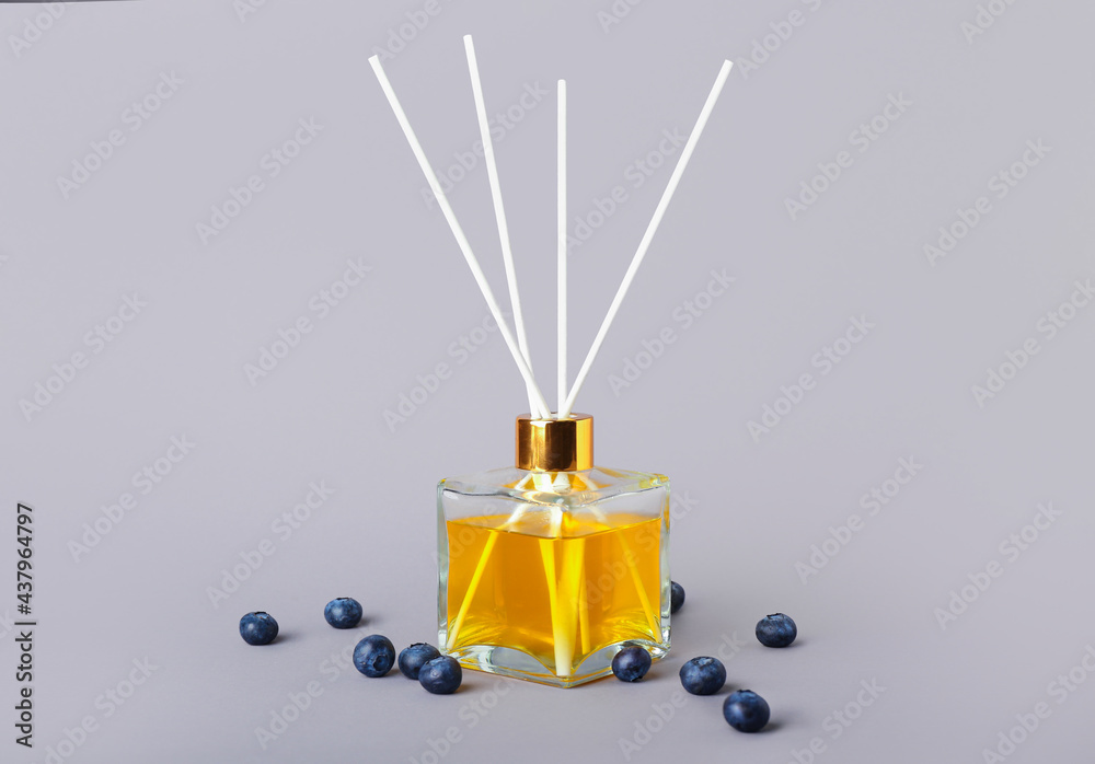 Reed diffuser with blueberries on grey background