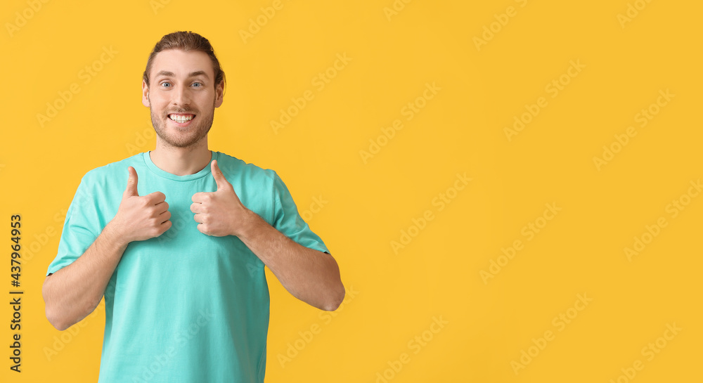 Handsome man showing thumbs-up on color background