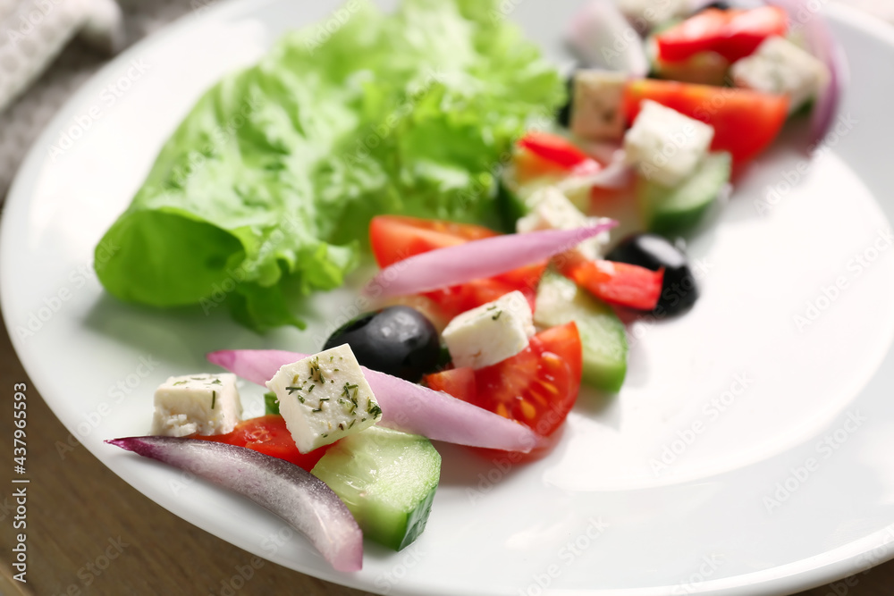 Plate of tasty Greek salad on wooden board, closeup