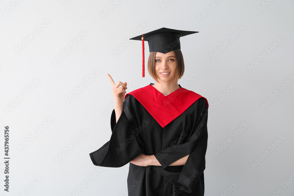 Female graduating student showing something on light background