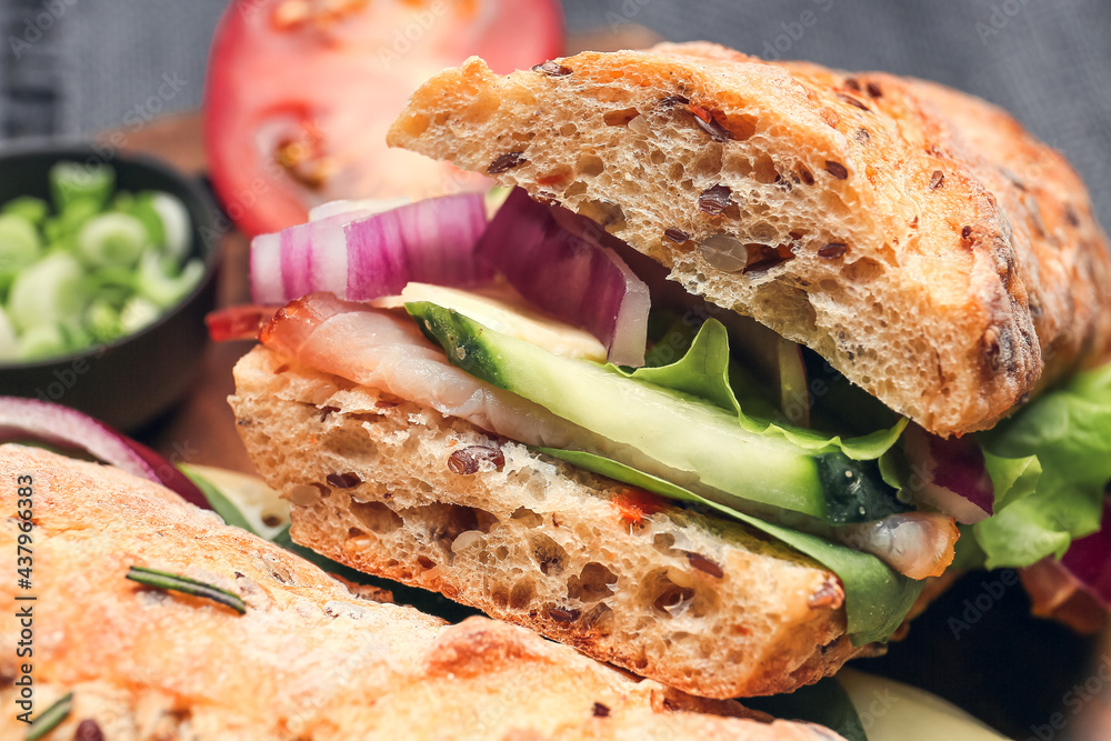 Board with tasty ciabatta sandwiches on dark background