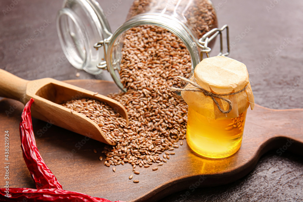 Composition with flax seeds, oil and chili peppers on dark background, closeup