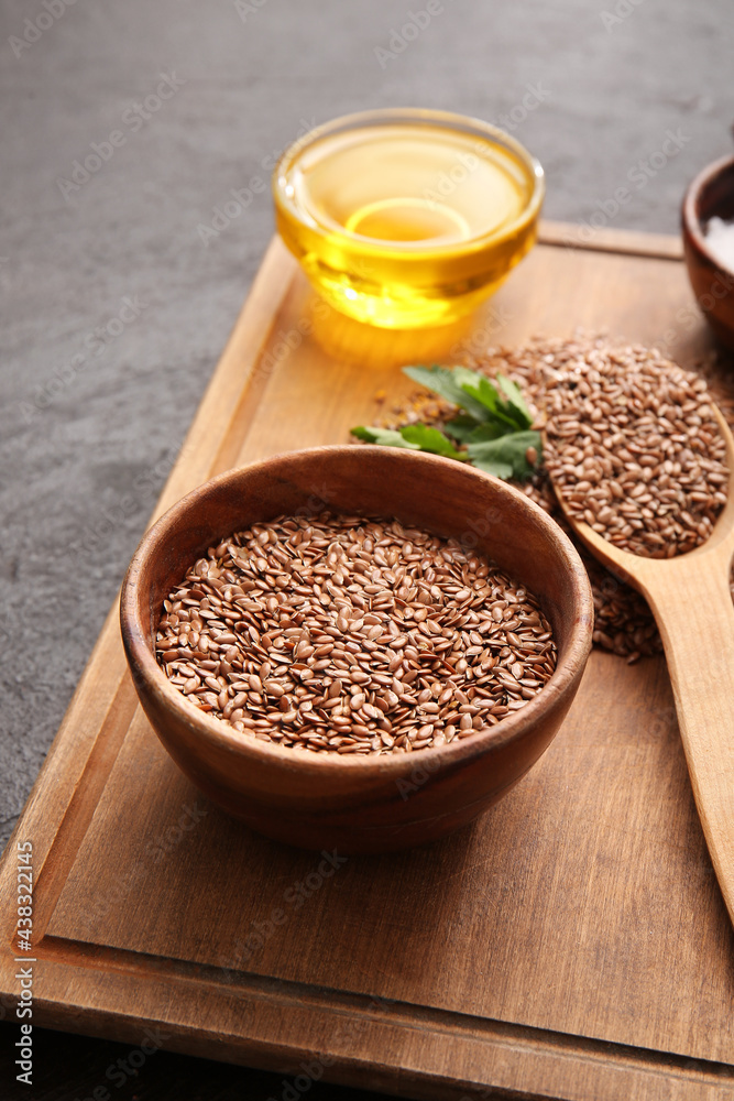 Board with flax seeds and oil on dark background