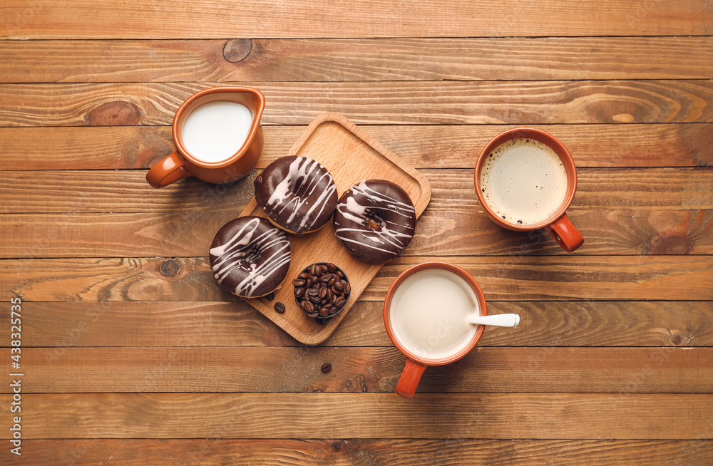 Cup of freshly brewed coffee and donuts on wooden table