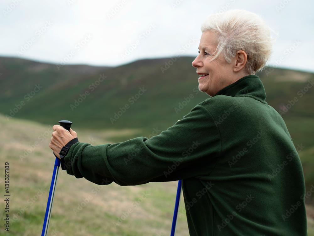 拄着登山杖行走的老年妇女