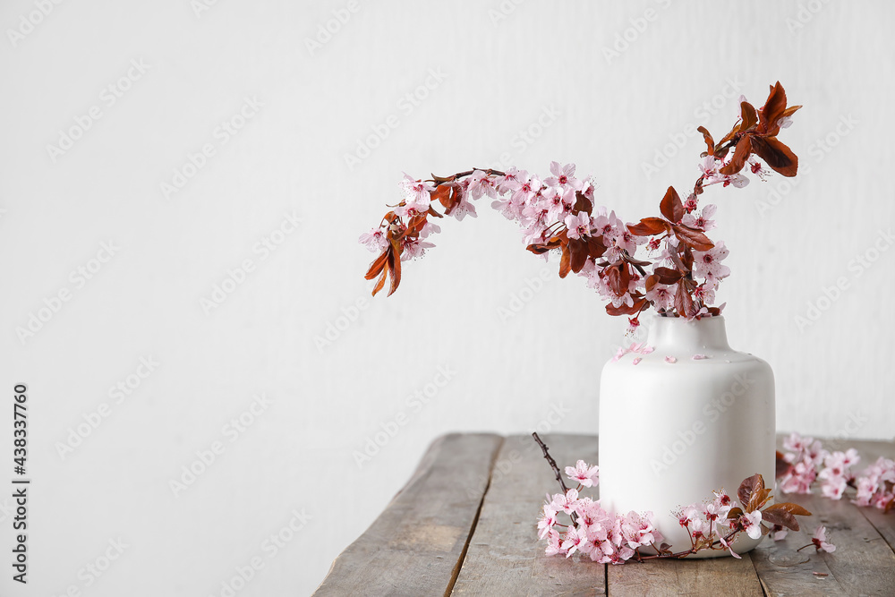 Vase with beautiful blossoming branches on wooden table