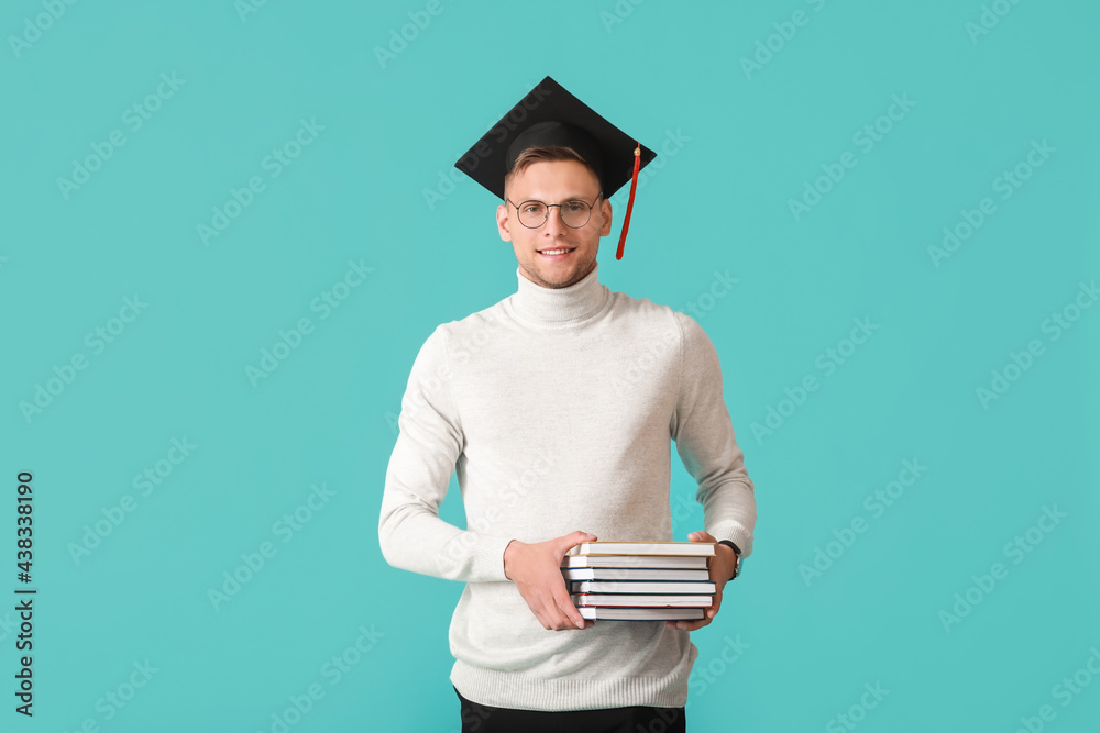 Male graduating student with books on color background