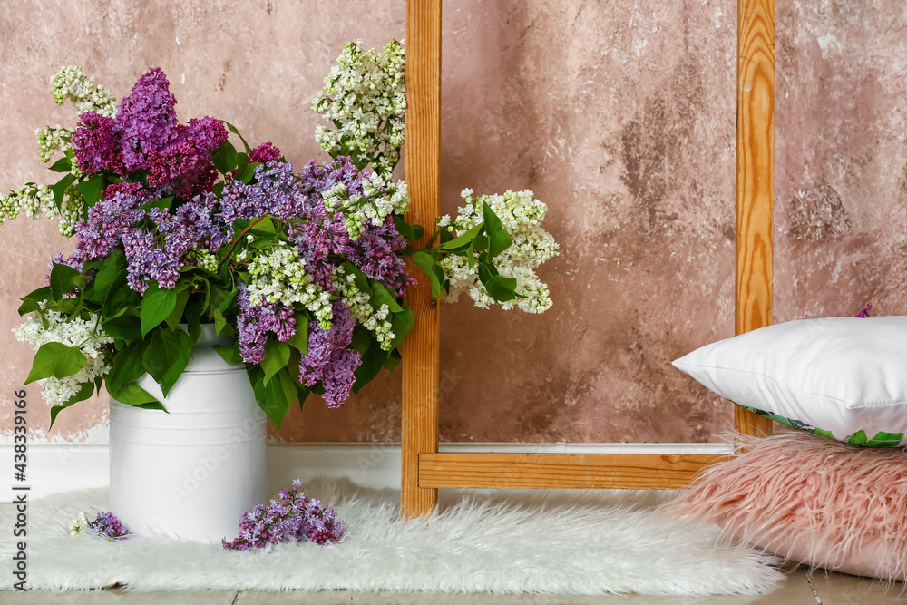 Vase with lilac flowers on floor near color wall