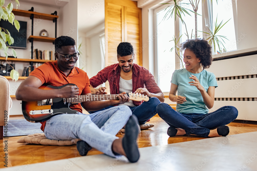 Adult people, being impressed by their friend playing the guitar.