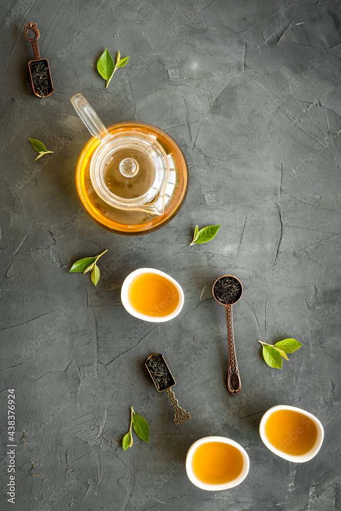 Tea green leaves with teapot and cups, top view. Tea ceremony concept.