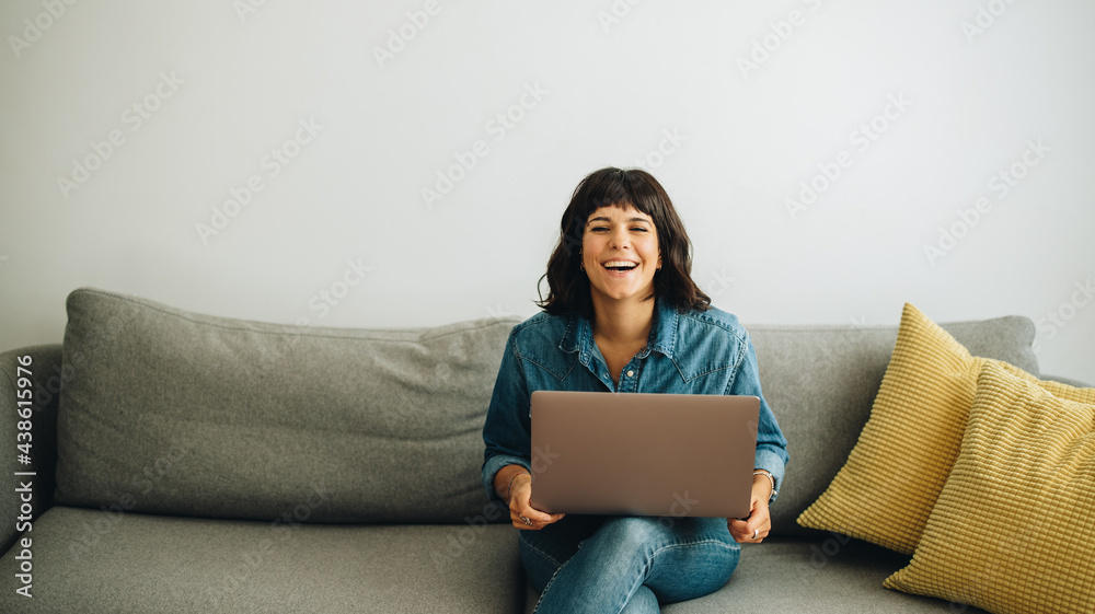 Happy businesswoman with laptop sitting in lobby